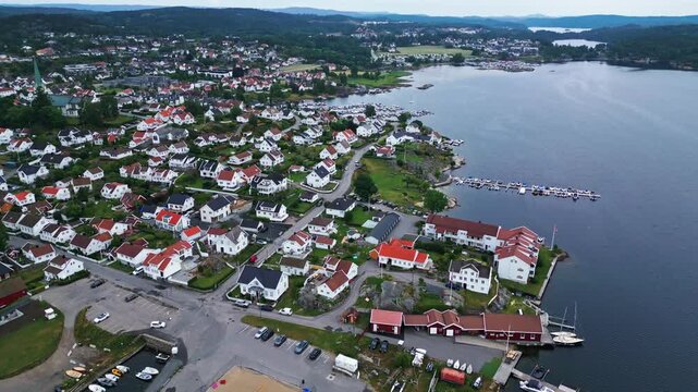 Aerial view of the coastal town with white houses, harbor, and boats along the coastline in Lillesand, Agder, Norway.