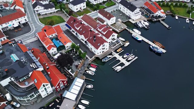 Aerial view of Lillesand harbor with white wooden houses, red roofs, and boats docked at the pier in Lillesand, Agder, Norway.