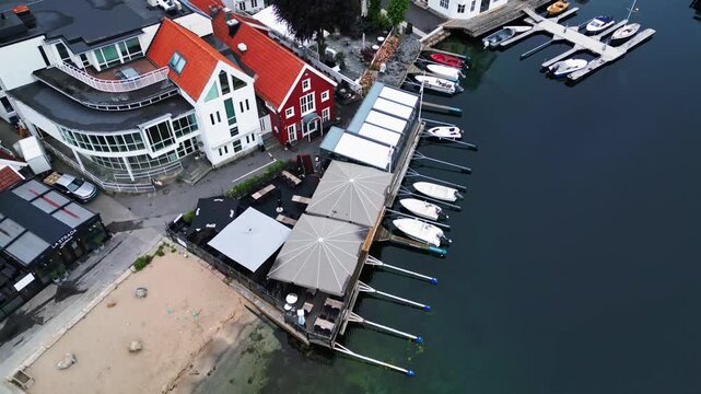 Aerial view of Lillesand harbor with white buildings featuring red roofs and boats docked at piers in Lillesand, Agder, Norway.
