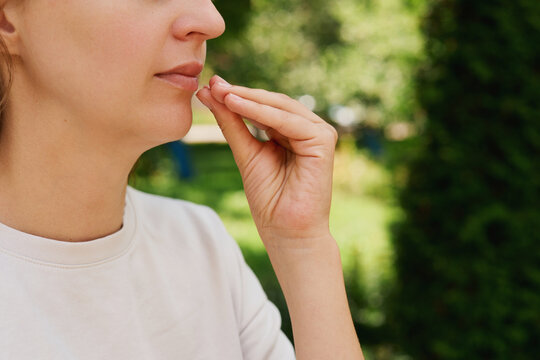 A person is using sign language in a park. The surroundings show green trees and grass as the individual communicates with their hands