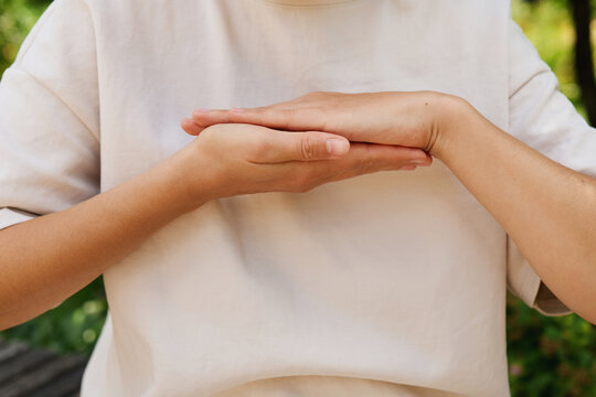 A person uses hands to communicate through sign language in a lush outdoor area. The focus is on the gestures being made without any spoken words