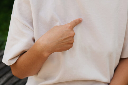 A person is using sign language to express an idea while seated in a garden. Their hand points to their chest, showing a sign or gesture in communication