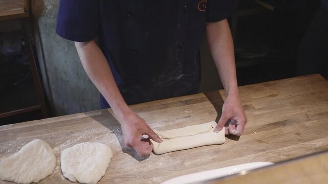 Close-up of a master working with pizza or khachapuri dough. Manually forming the base and sides on a wooden work surface.