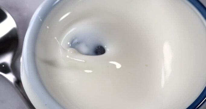 Blueberry falling into a bowl of milk with splash in super slow motion