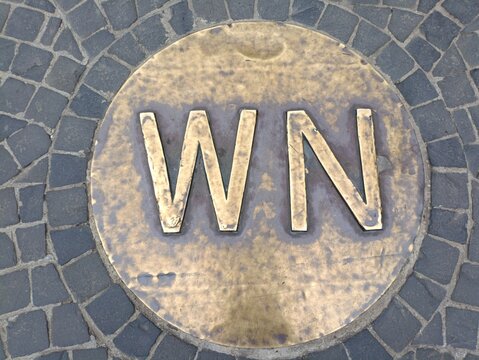 Vintage brass plaque with letter "WN" embedded in stone pavement at Ba Na Hills, Vietnam

