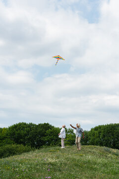 Joyful seniors embrace summer happiness while flying a colorful rainbow kite