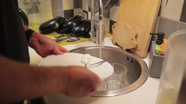 Man washing dishes at home, promoting shared chores and modern family equality