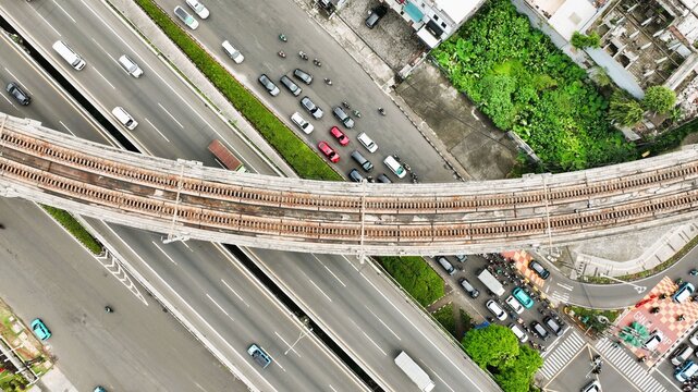 Aerial view of the elevated MRT track crossing over the busy highway with dense traffic and urban greenery in Cilandak, Jakarta, Indonesia.