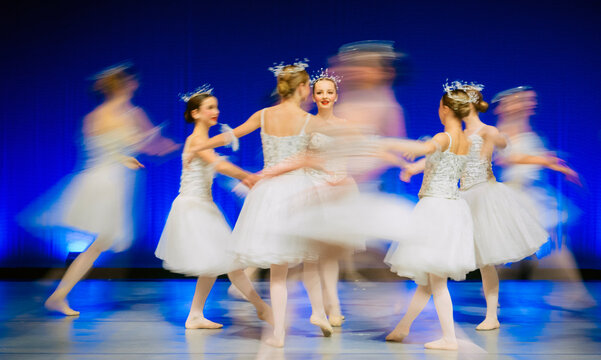 Young ballet dancers performing together on stage in white tutus