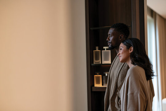An intimate moment captured of a couple interacting in front of a display of perfume bottles, emphasizing their connection and the shared experience of fragrance.
