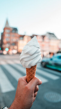 Hand h&auml;lt Vanille Softeis in Waffel vor unscharfer Altstadt von Kopenhagen