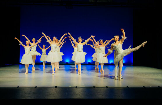 Ballet dancers perform holiday-themed dance on stage in white tutus