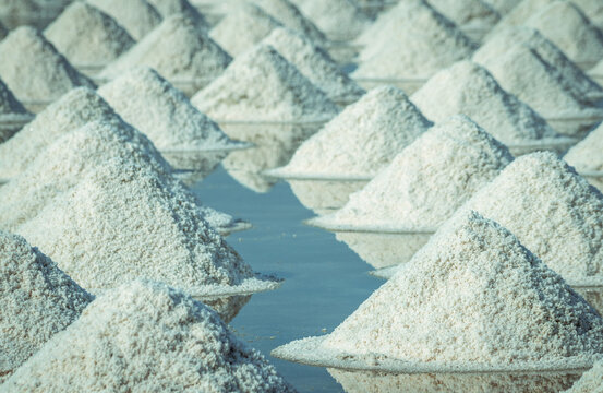 Sea salt piles in traditional salt farm during solar evaporation process for natural sodium chloride production and sustainable mineral harvesting in Thailand. Organic sea salt crystallization.