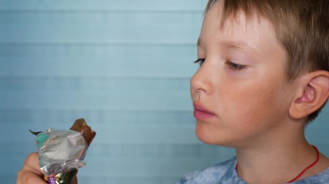 Close-up of a cute boy eating a trendy healthy protein bar filled with crispy Middle Eastern kunafa crunch and green pistachio paste, enjoying a nutritious sweet fitness snack