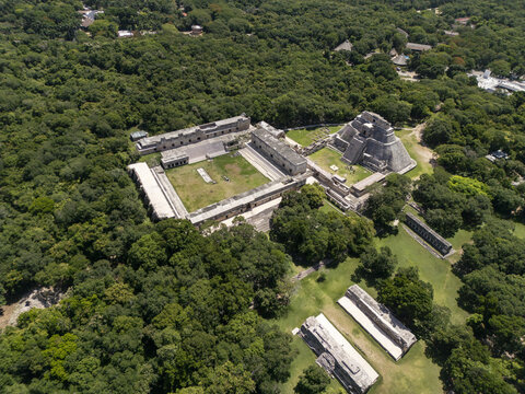 Aerial view of the ancient Mayan archaeological site of Uxmal featuring the Pyramid of the Magician and the Nunnery Quadrangle surrounded by lush jungle in Uxmal, Yucatan, Mexico.