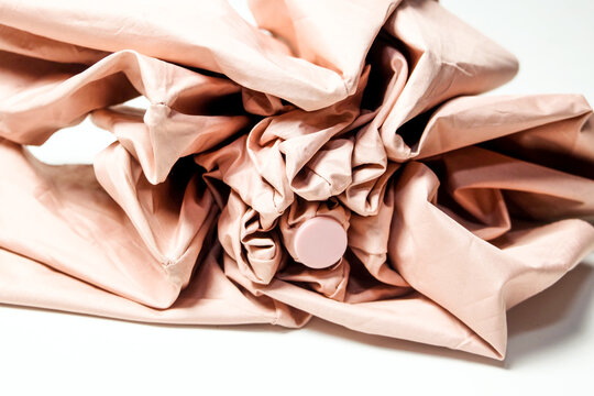 close-up macro view of the crumpled, folded pink fabric layers of a compact umbrella.