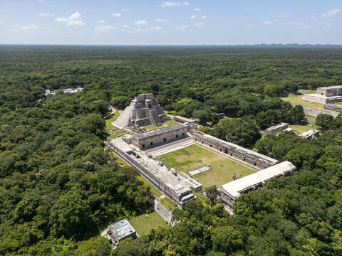 Aerial view of the ancient Mayan city of Uxmal, featuring the Pyramid of the Magician and the Nunnery Quadrangle surrounded by dense jungle in Uxmal, Yucatan, Mexico.