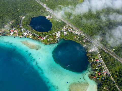 Aerial view of Cenote Cocalitos in the Bacalar Lagoon, featuring deep blue cenotes contrasting with turquoise shallow waters, surrounded by lush jungle in Bacalar, Quintana Roo, Mexico.
