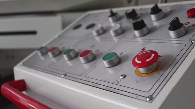 Close-up of the machine control panel. Buttons, switches and an emergency button for starting, stopping and adjusting the equipment.