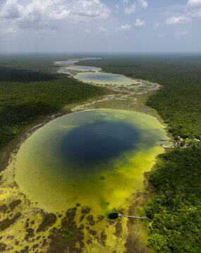 Aerial view of the Siijil Noh Ha cenote system surrounded by dense tropical jungle, featuring deep blue water and vibrant green vegetation in Felipe Carrillo Puerto, Quintana Roo, Mexico.