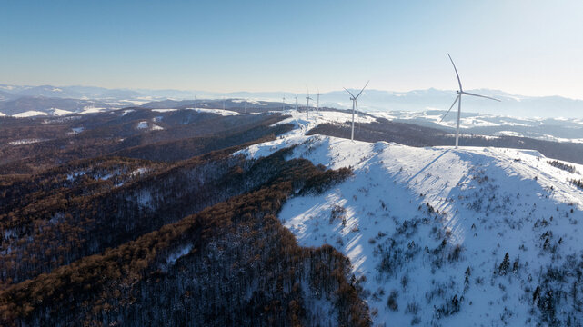 Aerial view of snow-covered hills with wind turbines in a winter landscape