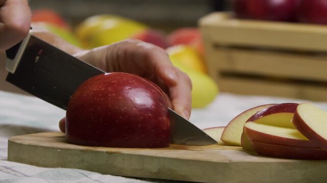 Red apple being sliced up on cutting board - closeup, slow motion
