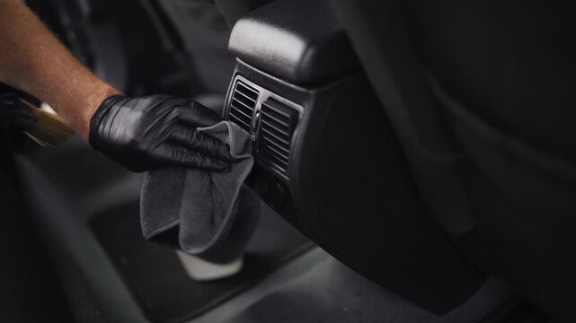 Automotive service technician performing meticulous interior detailing on modern vehicle, demonstrating expert workmanship, premium cleaning standards and high-quality automotive maintenance.