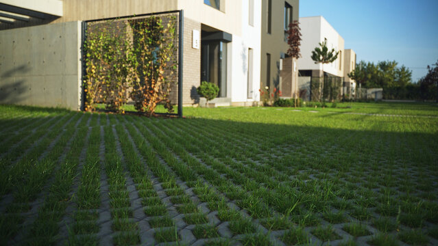 Modern suburban community with eco-friendly green parking lot interlocking pavers and contemporary houses under blue sky