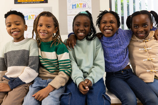 African American youth students sitting on bench in classroom, smiling at camera with MATH poster