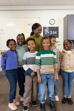 African American woman teacher with students standing at front of classroom near whiteboard