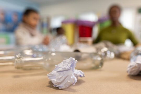 African American female teacher and youth sitting at school craft table crumpled paper in front