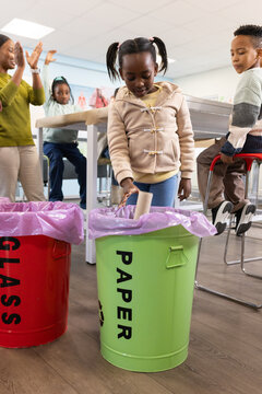Teacher and kids clapping, watching child placing cardboard tube into green PAPER bin in classroom
