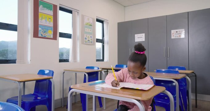 Child in pink top doing schoolwork with yellow pencil at school desk camera zooming causing smile