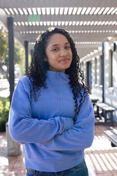 African American teen female standing under slatted pergola on campus path showing pullover zipper