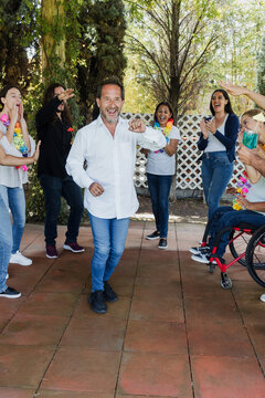 senior mexican man dancing with latin friends in a party in terrace outdoors in Mexico Latin America. Diverse Hispanic people men and women multi age having fun