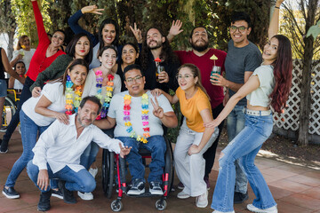 Fototapeta premium portrait of large group of latin friends with people with disabilities in wheelchair having a party in a terrace outdoors in Mexico Latin America, young hispanic multi age family in inclusion concept