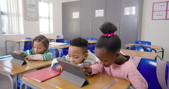 Diverse students at front-row desks, girl in pink top tapping center tablet, urging peers to engage