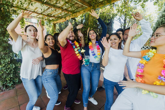 large group of latin friends dancing in a party in terrace outdoors in Mexico Latin America. Diverse Hispanic people men and women multi age having fun