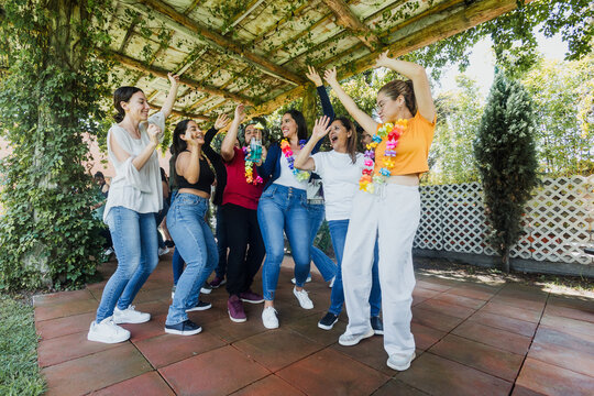 large group of latin friends dancing in a party in terrace outdoors in Mexico Latin America. Diverse Hispanic people men and women multi age having fun