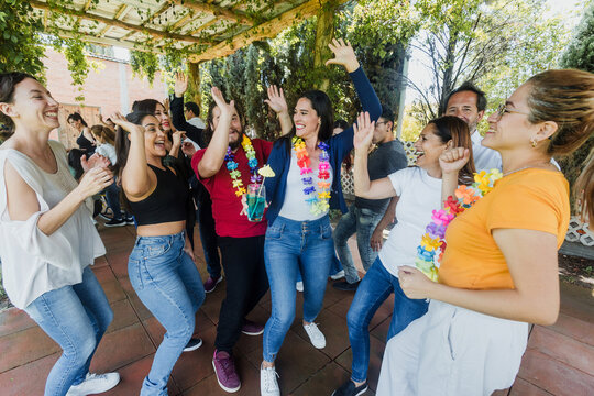 large group of latin friends dancing in a party in terrace outdoors in Mexico Latin America. Diverse Hispanic people men and women multi age having fun