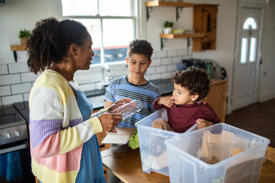 Mother teaching children to recycle in home kitchen