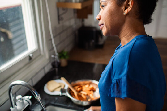 Woman preparing dinner in a home kitchen by the window