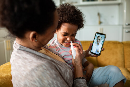 Caregiver gives child nasal spray during telehealth call at home
