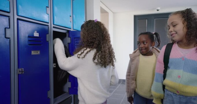 Diverse female children entering school hall main girl opening locker taking black backpack leaving