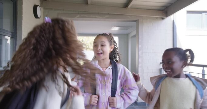 African American teen girls standing with backpacks at school as friends running up between classes