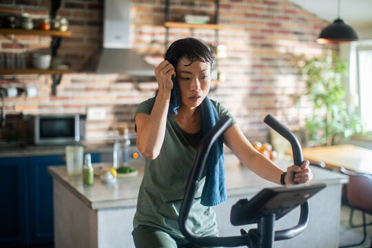 Woman working out on exercise bike in home kitchen