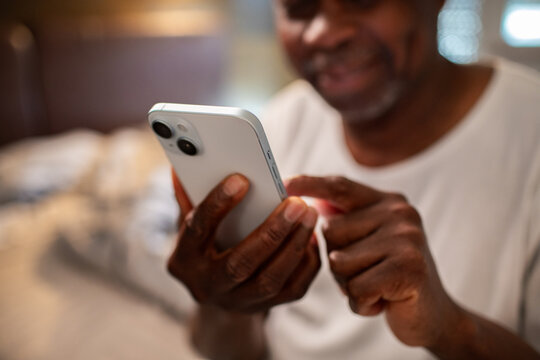 Senior man using smartphone in bedroom at home