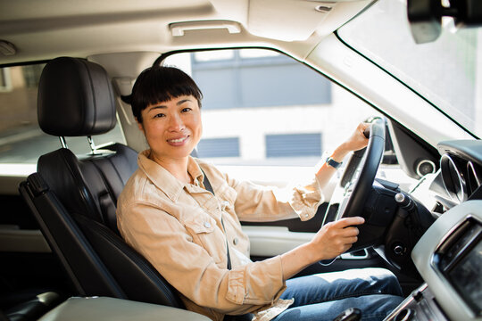 Smiling woman driving suv in city street