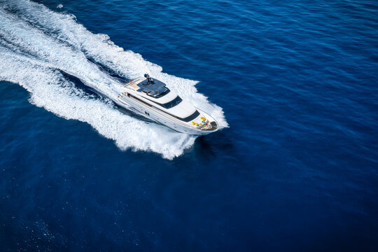 Aerial view of an modern luxury yacht cruising over calm ocean with high speed