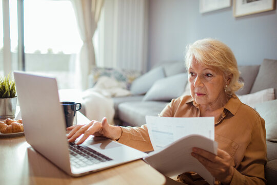 Senior woman paying bills online at home